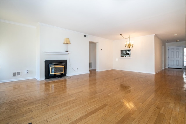 unfurnished living room featuring visible vents, an inviting chandelier, light wood-style flooring, and crown molding