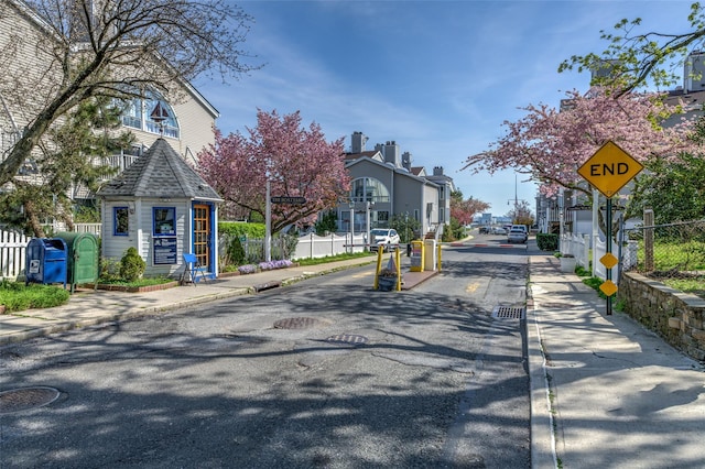 view of road with sidewalks, a residential view, curbs, and traffic signs