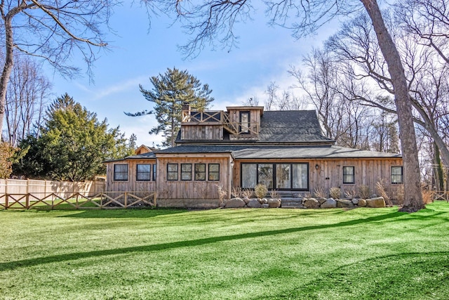 rear view of property with fence and a lawn