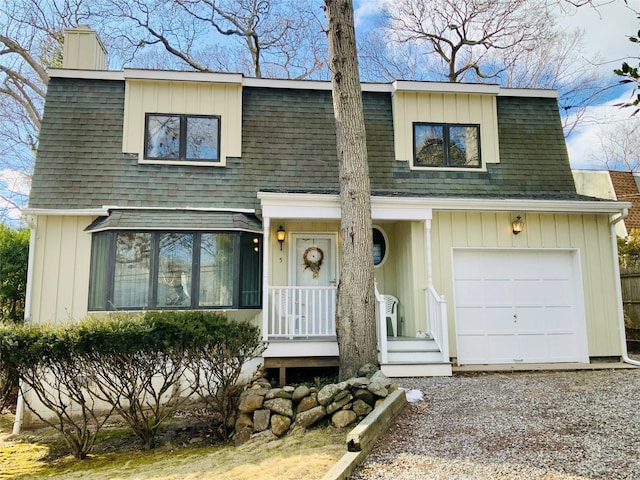 view of front facade with a shingled roof, driveway, and a chimney