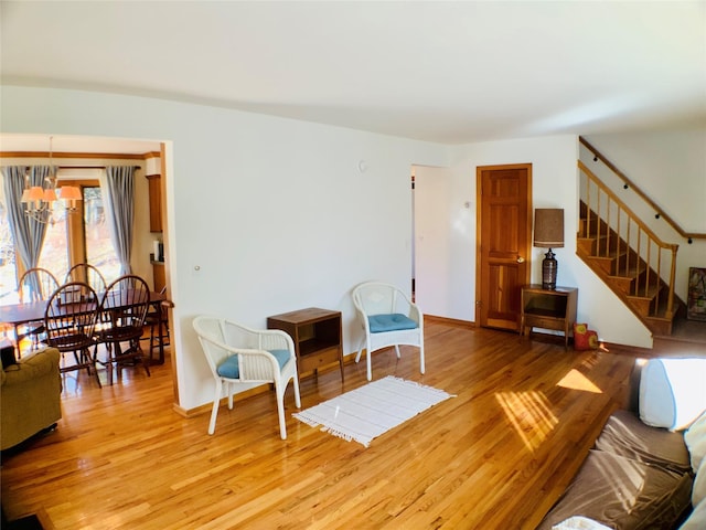 living area with stairs, baseboards, a notable chandelier, and light wood-style floors