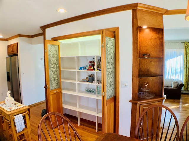 interior space featuring recessed lighting, light wood-type flooring, stainless steel fridge, and crown molding