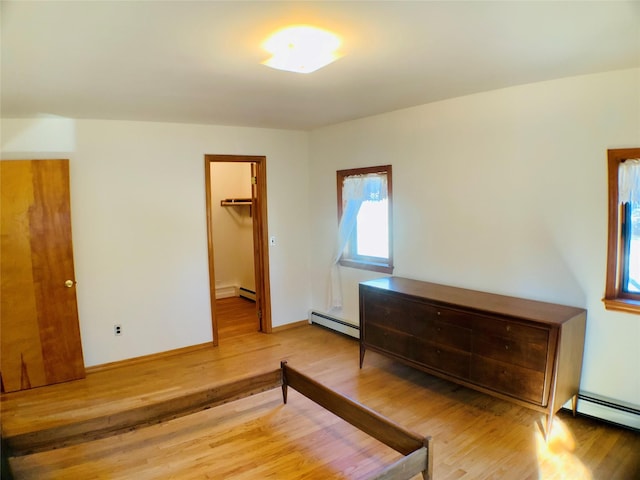 unfurnished bedroom featuring a baseboard heating unit and wood finished floors