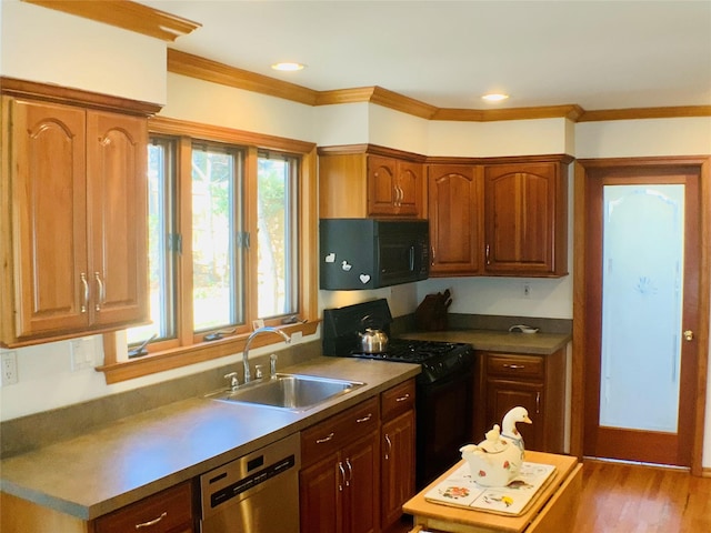 kitchen featuring wood finished floors, a sink, ornamental molding, black appliances, and brown cabinetry