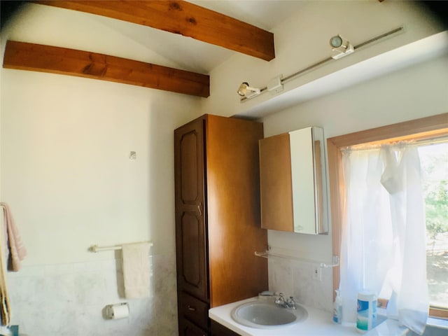 bathroom featuring a sink and lofted ceiling with beams