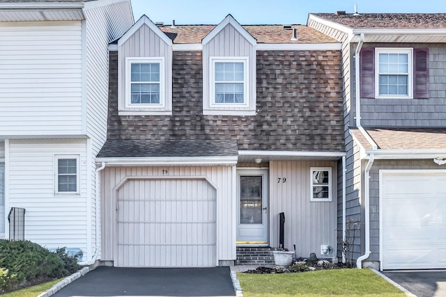 view of property with driveway, a garage, and roof with shingles