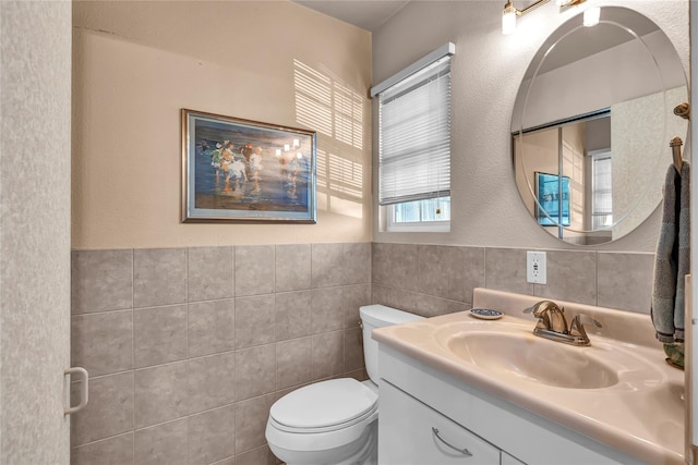 bathroom with toilet, wainscoting, tile walls, and vanity