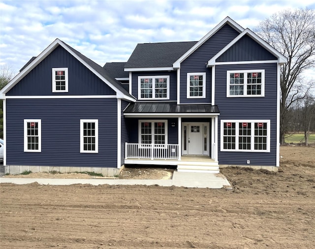 view of front facade featuring covered porch, a shingled roof, metal roof, and a standing seam roof