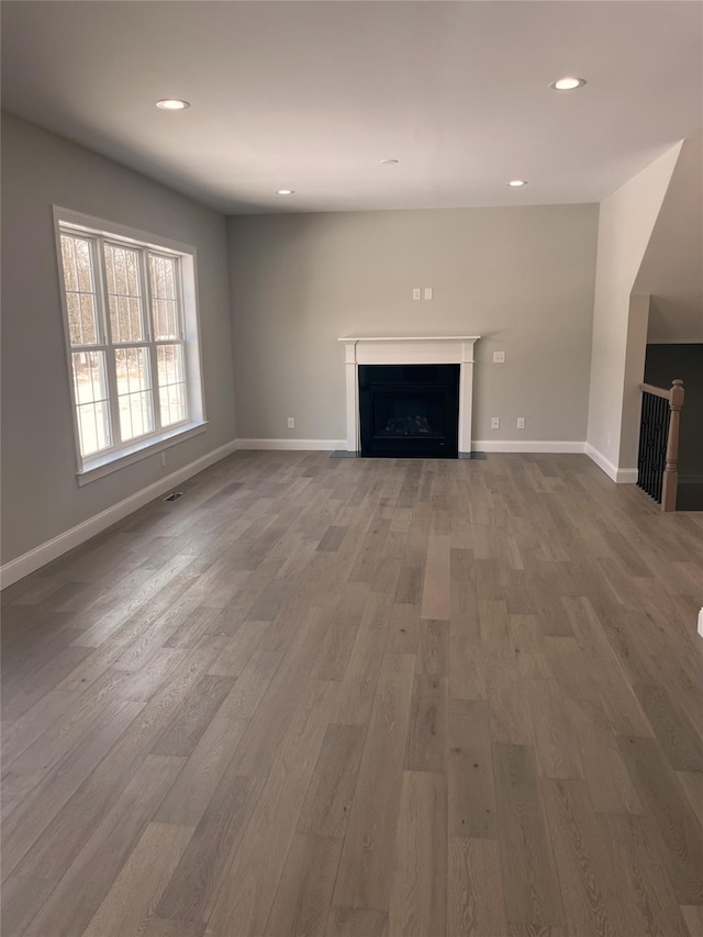 unfurnished living room with a fireplace, wood finished floors, and baseboards