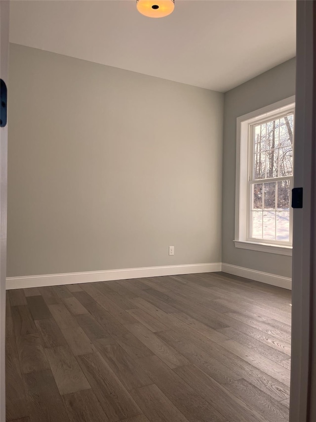 empty room with baseboards and dark wood-type flooring