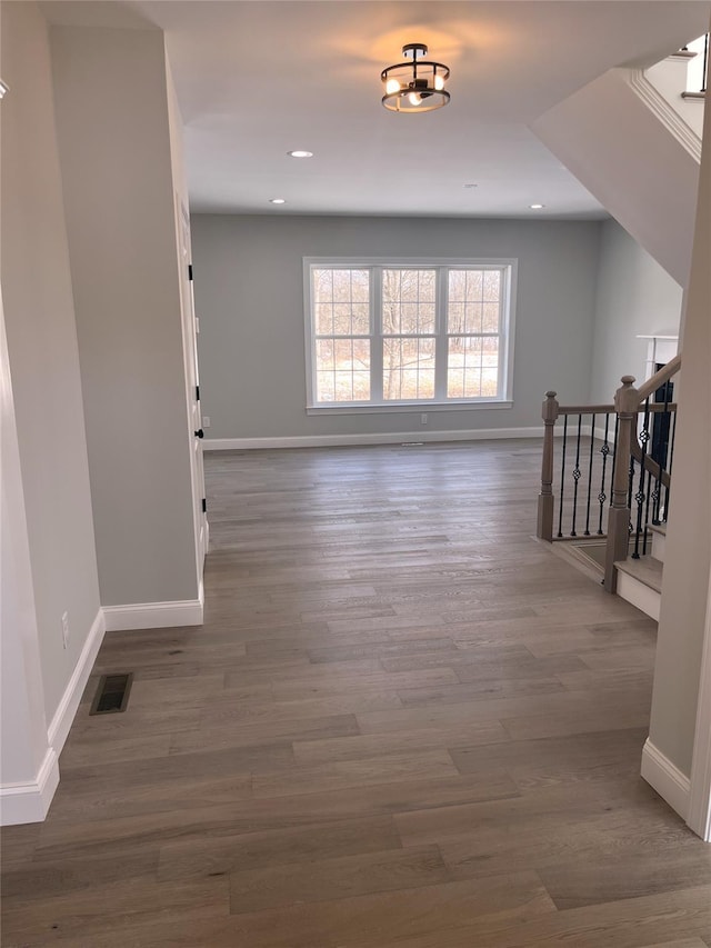 spare room featuring stairs, wood finished floors, visible vents, and baseboards