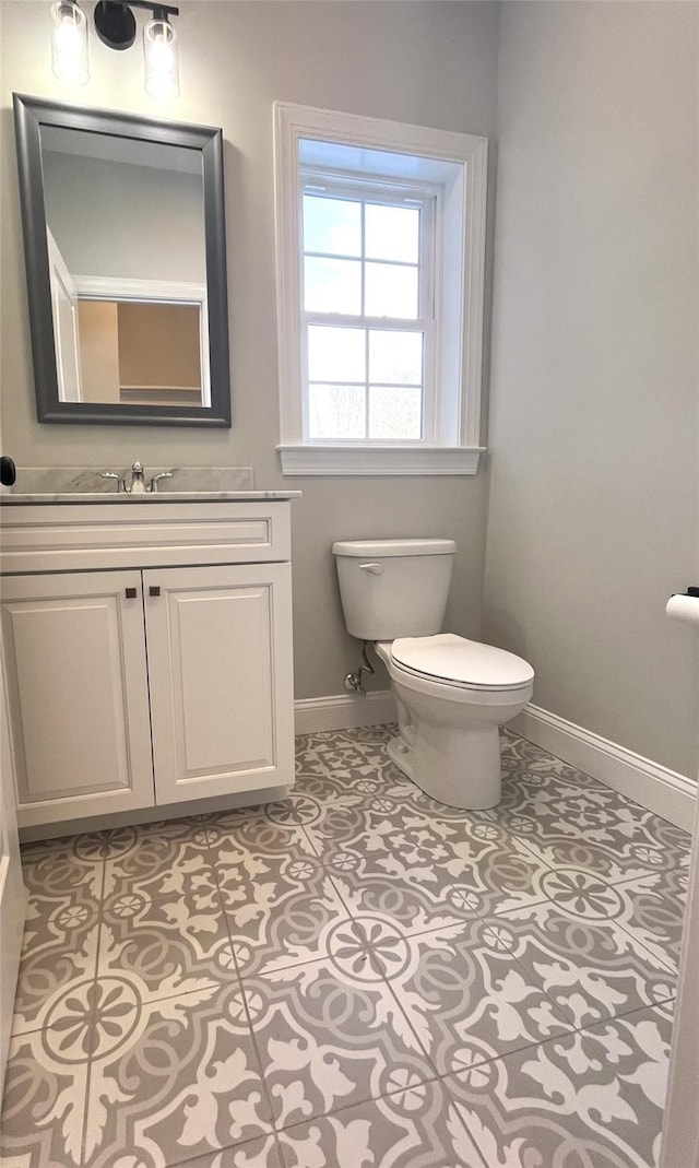 bathroom with tile patterned flooring, baseboards, vanity, and toilet