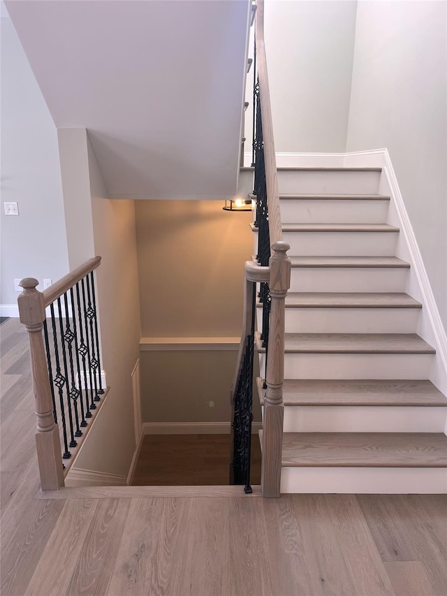 stairway with baseboards and wood finished floors