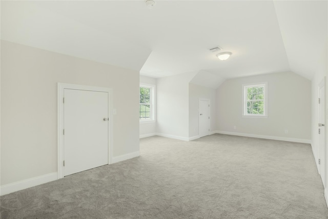 bonus room featuring a wealth of natural light, light carpet, vaulted ceiling, and baseboards