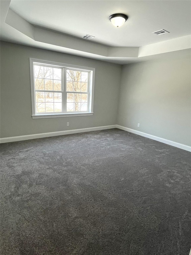 empty room featuring baseboards, visible vents, and dark carpet