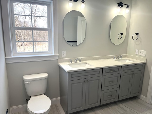 bathroom featuring double vanity, a sink, and toilet