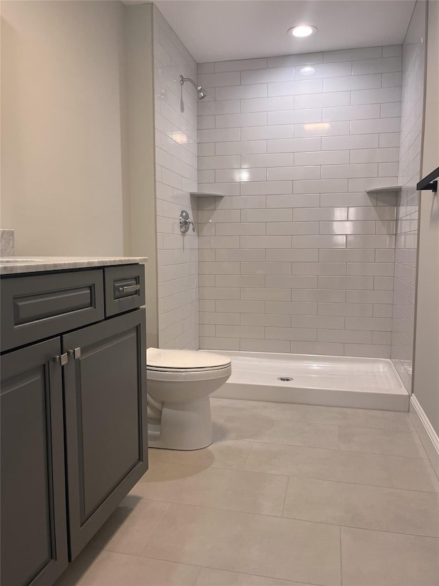 bathroom featuring toilet, a tile shower, and vanity