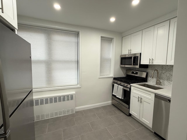 kitchen featuring stainless steel appliances, a sink, white cabinets, and radiator