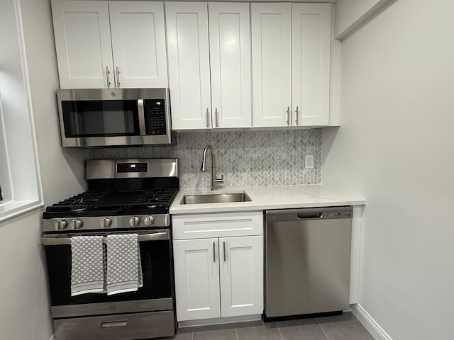 kitchen featuring tasteful backsplash, appliances with stainless steel finishes, white cabinets, and a sink