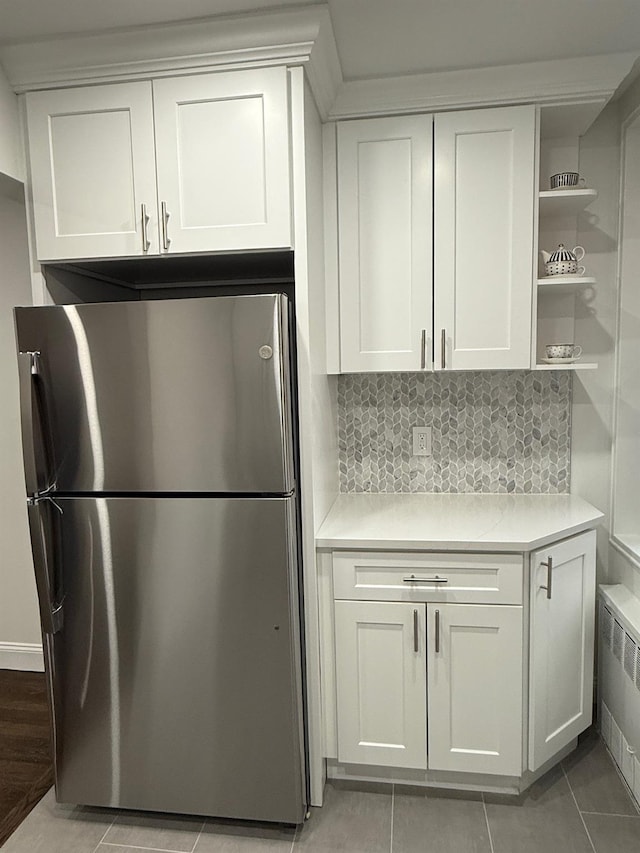 kitchen featuring light countertops, freestanding refrigerator, white cabinetry, and radiator heating unit