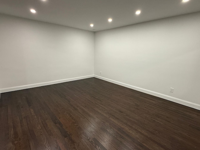 spare room featuring recessed lighting, dark wood-style flooring, and baseboards