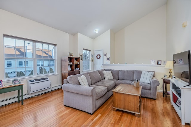 living room featuring high vaulted ceiling, light wood-type flooring, a wall mounted air conditioner, and a baseboard radiator