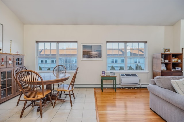 dining room with a baseboard heating unit, light wood-type flooring, and a wealth of natural light