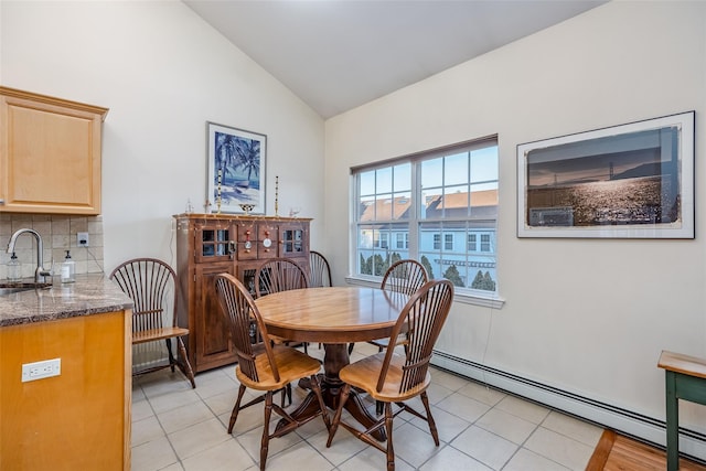 dining area featuring lofted ceiling, light tile patterned floors, and a baseboard radiator