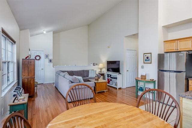 dining space with high vaulted ceiling, light wood-type flooring, and baseboards