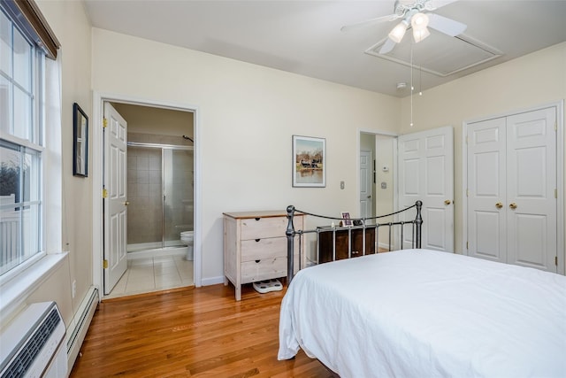 bedroom with attic access, connected bathroom, baseboard heating, light wood-type flooring, and a closet