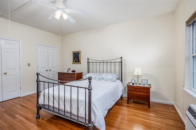 bedroom featuring attic access, heating unit, baseboards, and wood finished floors