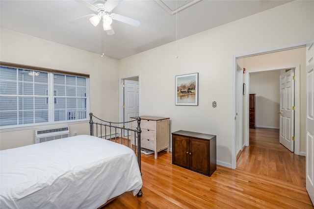 bedroom featuring a wall unit AC, a baseboard heating unit, baseboards, light wood finished floors, and attic access