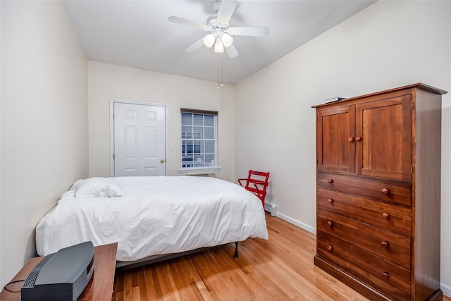 bedroom featuring ceiling fan, a baseboard radiator, baseboards, and light wood-style flooring