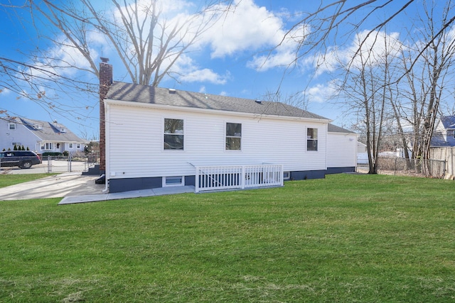 back of house featuring a chimney, fence, and a lawn