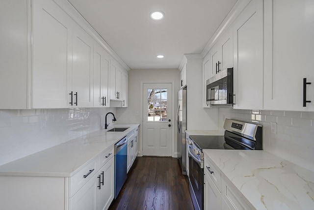 kitchen featuring light stone counters, appliances with stainless steel finishes, dark wood-type flooring, and white cabinetry