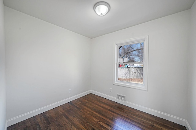 unfurnished room with dark wood-style flooring, visible vents, and baseboards