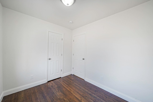 empty room with dark wood finished floors and baseboards