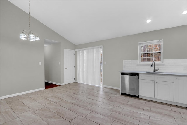 kitchen featuring white cabinets, lofted ceiling, light countertops, stainless steel dishwasher, and a sink