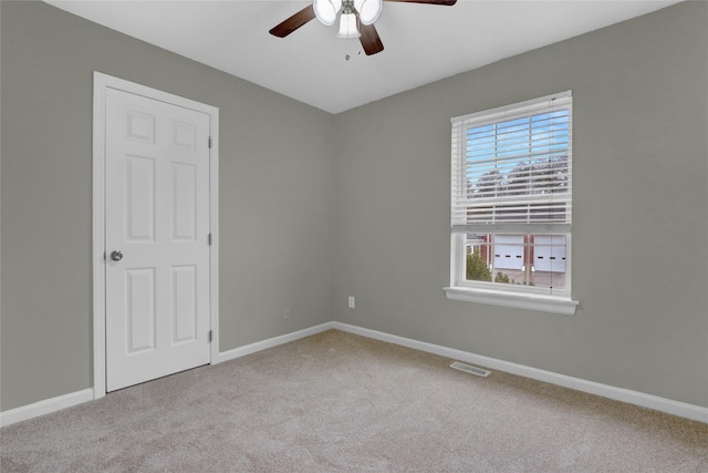 carpeted spare room with a ceiling fan, visible vents, and baseboards