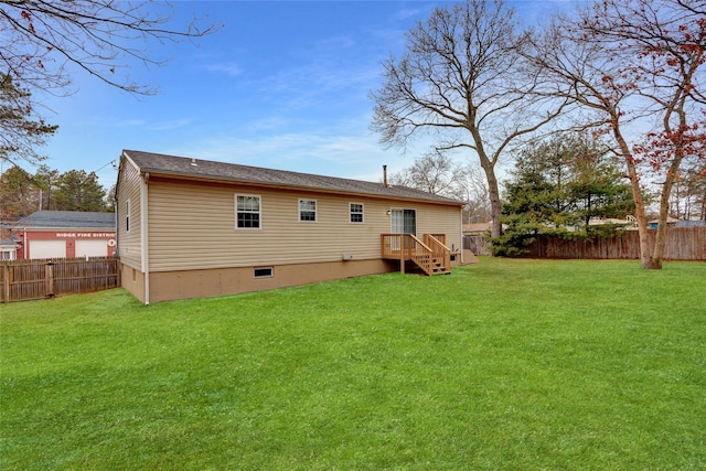 back of house with a fenced backyard and a lawn