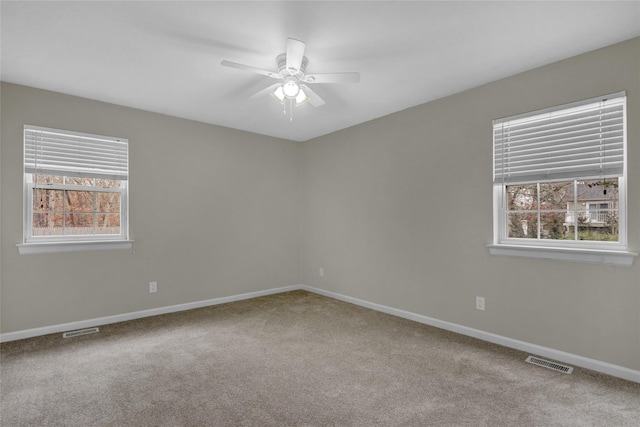 spare room with a healthy amount of sunlight, carpet, and visible vents