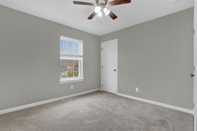 empty room featuring carpet floors, visible vents, baseboards, and ceiling fan