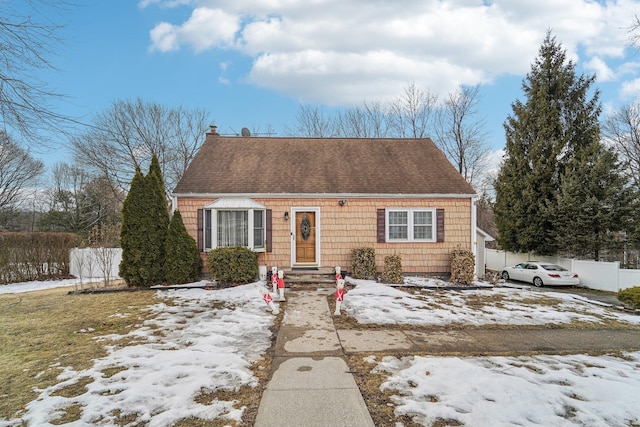 view of front of property featuring a chimney, fence, and roof with shingles