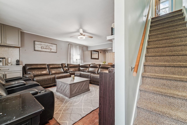 living area with ceiling fan and stairs