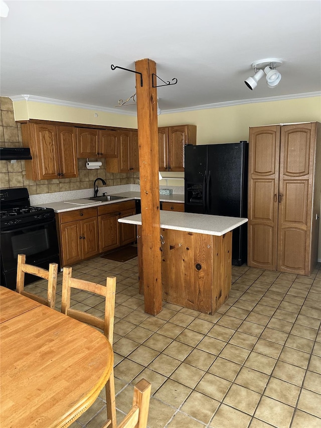 kitchen with black appliances, ornamental molding, light countertops, and a sink