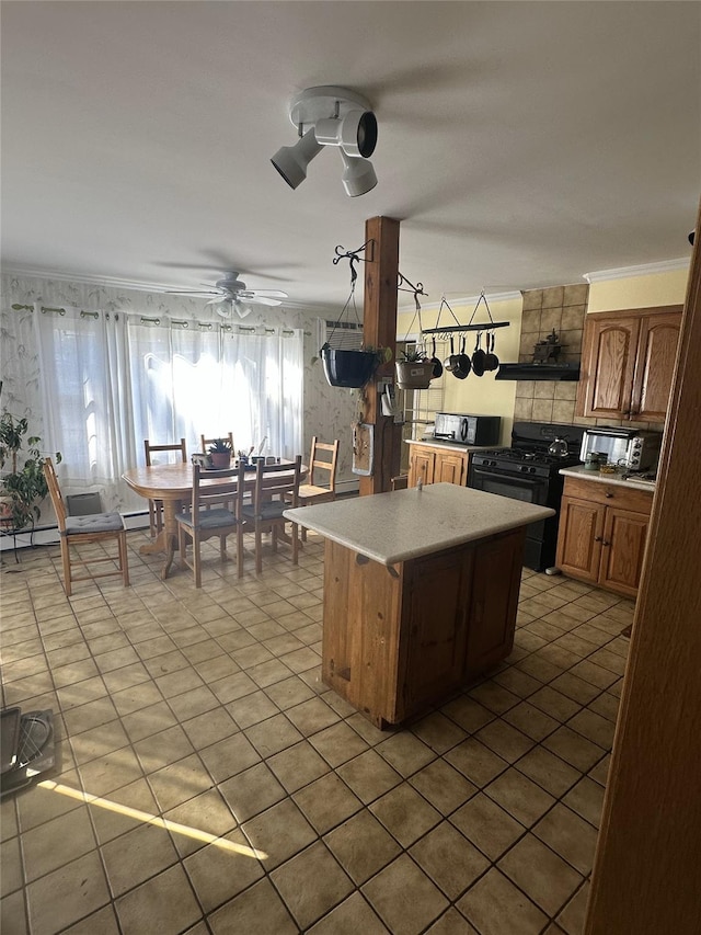 kitchen featuring ceiling fan, ornamental molding, a center island, light countertops, and black appliances