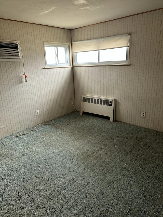 carpeted empty room with an AC wall unit and radiator