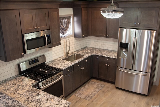 74 Wisconsin St, Long Beach, NY 11561 - kitchen featuring a sink, dark brown cabinets, light wood-style floors, decorative backsplash, and appliances with stainless steel finishes