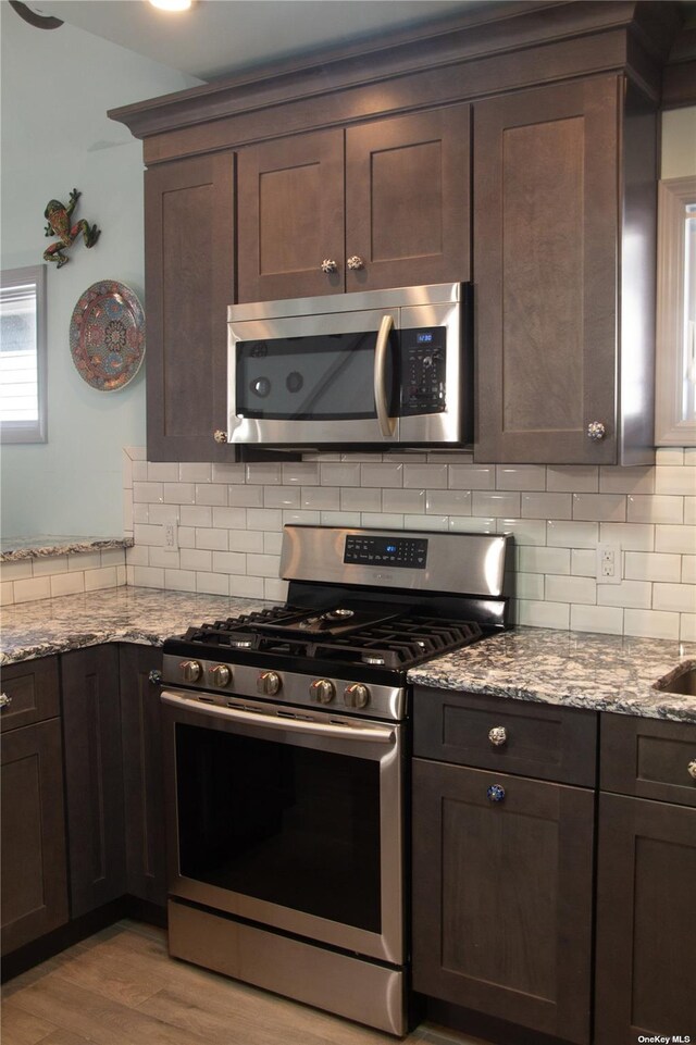 74 Wisconsin St, Long Beach, NY 11561 - kitchen with stainless steel appliances, dark brown cabinetry, light stone counters, and tasteful backsplash