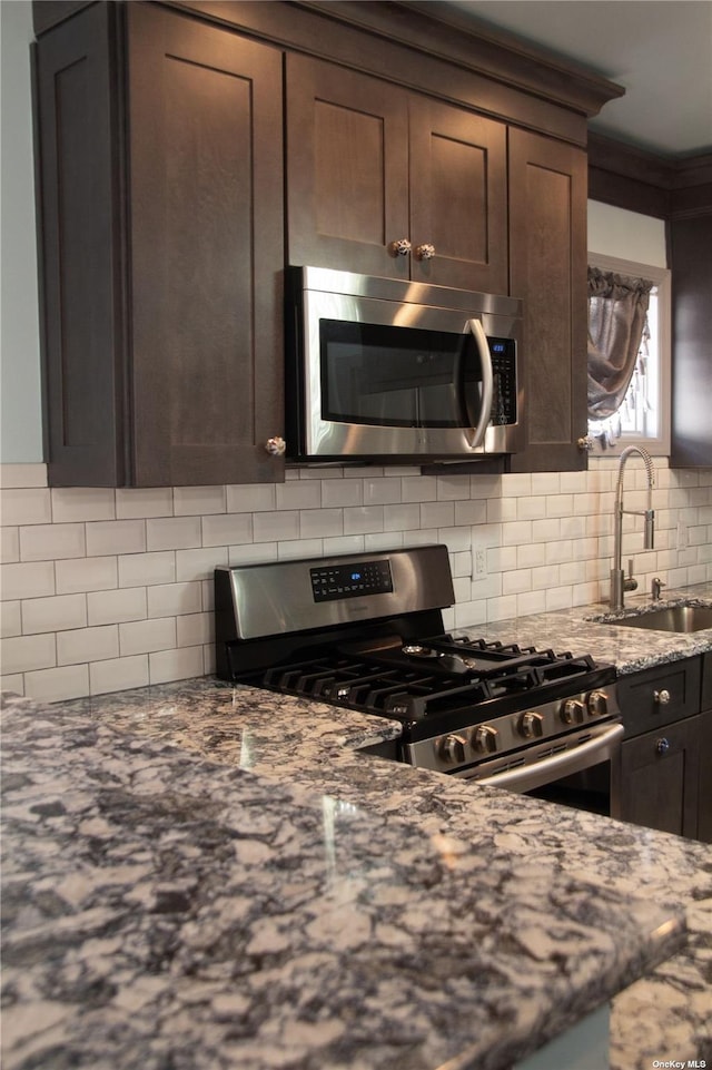 74 Wisconsin St, Long Beach, NY 11561 - kitchen with dark stone counters, tasteful backsplash, a sink, dark brown cabinetry, and stainless steel appliances